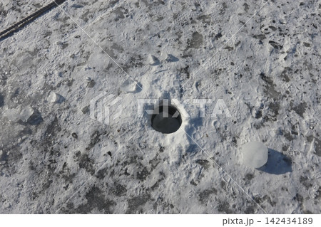 Frozen Ice Hole on Snowy Surface 142434189