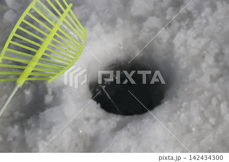 Ice Fishing Hole with Bright Yellow Rake 142434300