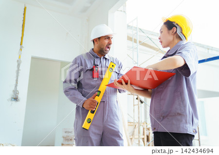 Diverse construction workers walking and reviewing plans at a building site 142434694