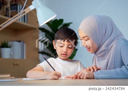 Muslim mother helping her son with homework at home Muslim mother helping her son with homework at home 142434784