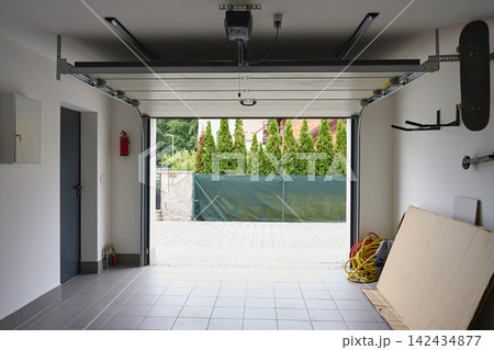 Open sectional garage door with automatic opener inside residential garage Open sectional garage door with automatic opener inside residential garage 142434877