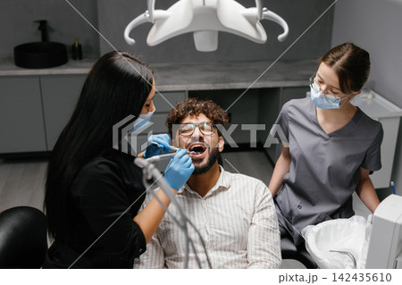 Dentist checking patient's teeth during oral examination Dentist checking patient's teeth during oral examination 142435610