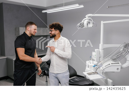 Dentist and patient shaking hands after successful treatment Dentist and patient shaking hands after successful treatment 142435625