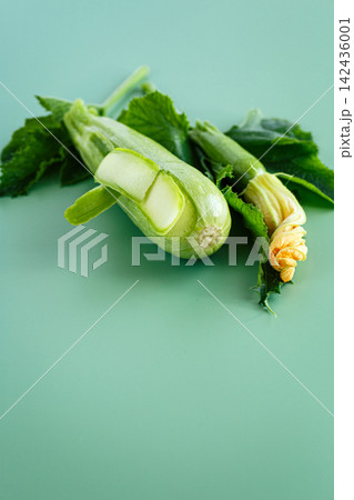 Fresh garden zucchini with leaves and blossom on soft green background Fresh garden zucchini with leaves and blossom on soft green background 142436001