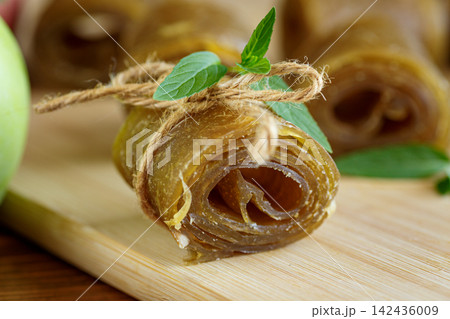 Healthy homemade apple leather rolls with green apple on rustic wooden background Healthy homemade apple leather rolls with green apple on rustic wooden background 142436009