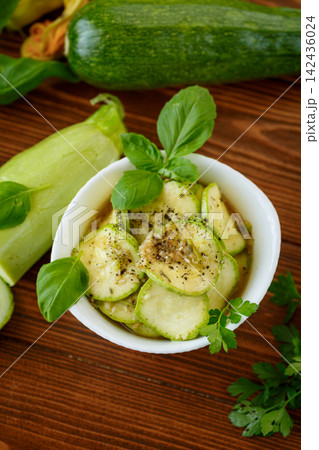 Marinated spicy zucchini with garlic herbs on wooden background Marinated spicy zucchini with garlic herbs on wooden background 142436024