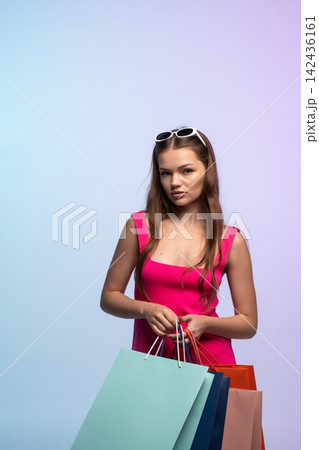 Young woman holding multiple paper shopping bags, reflecting retail therapy, fashion trends, consumption, and a modern lifestyle Young woman holding multiple paper shopping bags, reflecting retail therapy, fashion trends, consumption, and a modern lifestyle 142436161