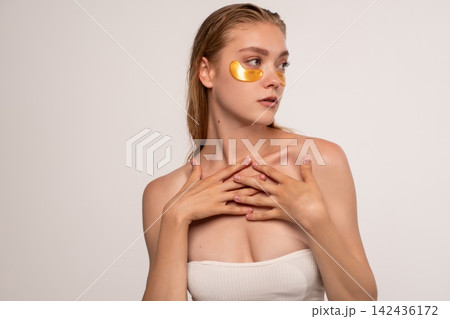 Young woman wearing gold eye patches for under eye skin care, enjoying wellness and facial beauty treatment Young woman wearing gold eye patches for under eye skin care, enjoying wellness and facial beauty treatment 142436172