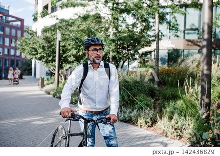 City commuter riding bike to office, wearing backpack and helmet. 142436829