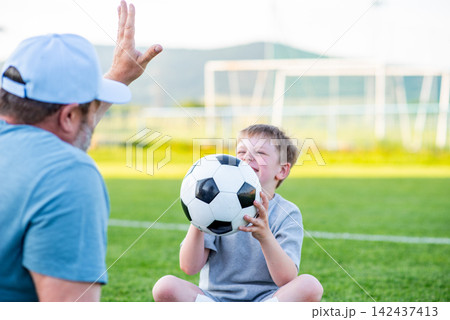 Dad and son sharing passion for football and active lifestyle. Dad and son sharing passion for football and active lifestyle. 142437413