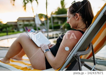 Woman with diabetes enjoying peaceful holiday while wearing continuous glucose monitor. 142437671