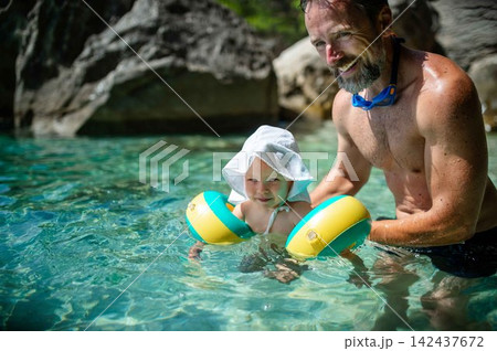 Father swimming with toddler daughter in shallow sea water during summer vacation. Father swimming with toddler daughter in shallow sea water during summer vacation. 142437672