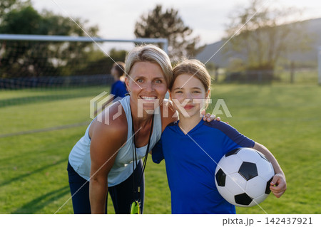 Girl football players hugging female coach, celebrating game success. Girl football players hugging female coach, celebrating game success. 142437921