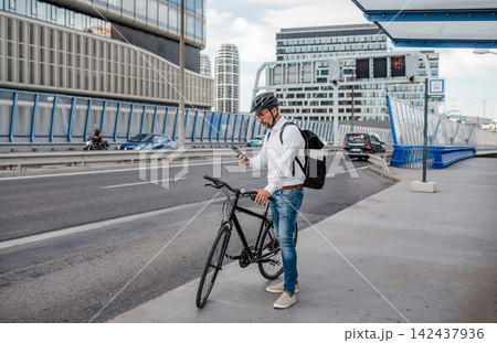 Manager on bike, reading text message on phone. Manager on bike, reading text message on phone. 142437936