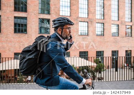 City commuter riding bike to office, wearing backpack and helmet. 142437949
