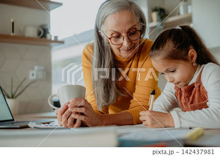 Grandmother helping granddaughter with homework, teaching her math. Grandmother helping granddaughter with homework, teaching her math. 142437981