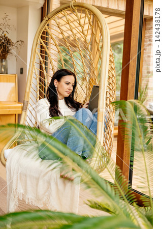 Relaxed woman taking a break, sitting in hanging chair. Relaxed woman taking a break, sitting in hanging chair. 142438178