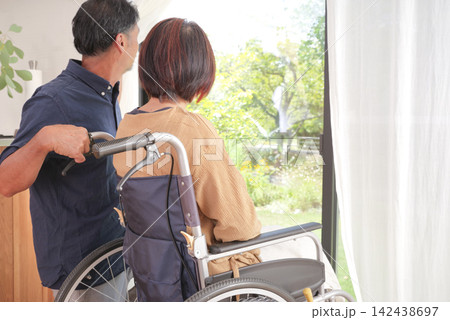 車椅子の妻に寄り添う中高年の夫 車椅子の妻に寄り添う中高年の夫 142438697
