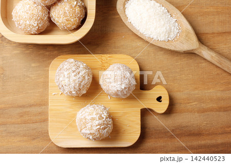 Brazilian coconut beijinho on a bamboo board atop a rustic wooden table. Traditional confectionery for parties and celebrations. 142440523