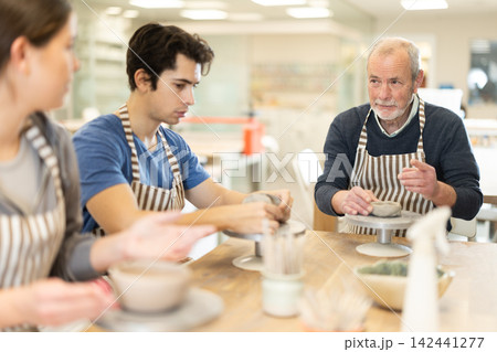 Young woman and man and elderly man crafting ceramics Young woman and man and elderly man crafting ceramics 142441277