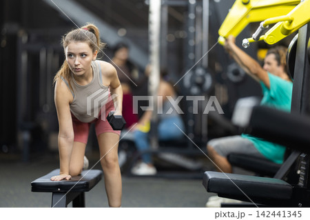 Young woman doing exercises with dumbbells in the gym 142441345