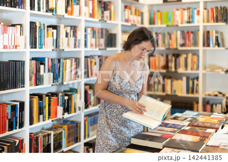 Adult woman choosing book in bookstore Adult woman choosing book in bookstore 142441385