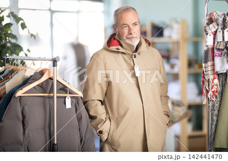 Elderly man trying on brown jacket in store 142441470