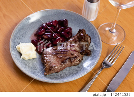 Meat steak with beans on a plate served with cutlery 142441525