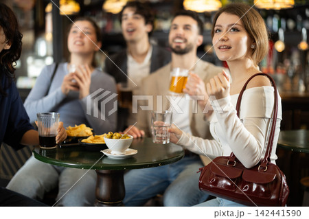 group of friends watching a game in a sports bar group of friends watching a game in a sports bar 142441590