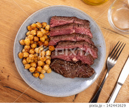 Delicious veal steak with chickpeas on served table in restaurant Delicious veal steak with chickpeas on served table in restaurant 142441629