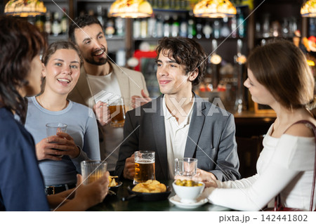 Group of friends at bar talking and drinking beer Group of friends at bar talking and drinking beer 142441802