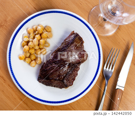 Delicious veal steak with chickpeas on served table in restaurant Delicious veal steak with chickpeas on served table in restaurant 142442050