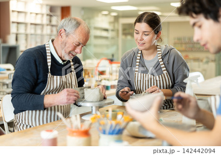 Young woman and man and elderly man crafting ceramics Young woman and man and elderly man crafting ceramics 142442094