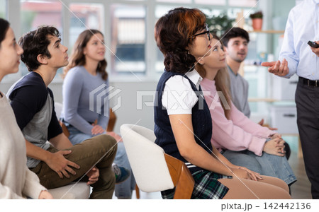 Group of young students listening during seminar in a modern classroom Group of young students listening during seminar in a modern classroom 142442136