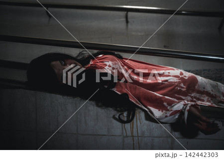 Halloween scary woman zombie wearing bloody costume lying on floor indoors during spooky night festival celebration with dark horror atmosphere and creepy monster theme Halloween scary woman zombie wearing bloody costume lying on floor indoors during spooky night festival celebration with dark horror atmosphere and creepy monster theme 142442303