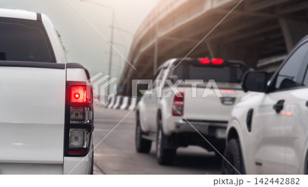 Rear side of pick up car with turn on brake light in concrete road. Wait in a line of traffic beneath an urban highway bridge during daytime. Rear side of pick up car with turn on brake light in concrete road. Wait in a line of traffic beneath an urban highway bridge during daytime. 142442882