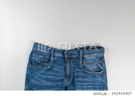 Blue denim jeans with pockets and zipper on a white background Blue denim jeans with pockets and zipper on a white background 142443407