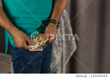 Man holding euro notes in his jeans pocket at home 142443429