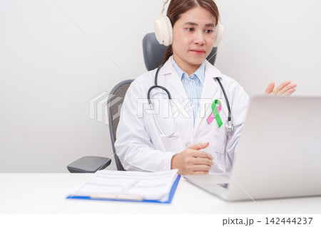 doctor using laptop for telehealth, online consultation and meeting about green and pink ribbon to patient for concept of October Metastatic Breast Cancer Awareness month, National Cancer Survivors doctor using laptop for telehealth, online consultation and meeting about green and pink ribbon to patient for concept of October Metastatic Breast Cancer Awareness month, National Cancer Survivors 142444237
