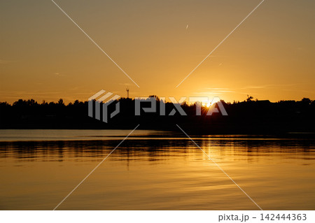 Golden sunset reflecting on a calm lake 142444363