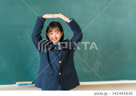 教室の黒板の前で丸印を作る制服姿の中学生,高校生の女の子 142445816