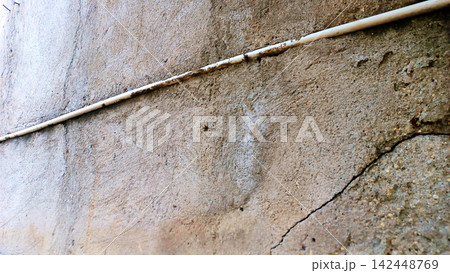 Textured concrete wall with pipes and cracks. 142448769