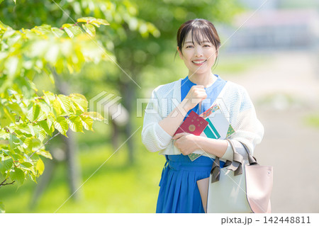 パスポートを抱え拳を握る笑顔の女性 パスポートを抱え拳を握る笑顔の女性 142448811
