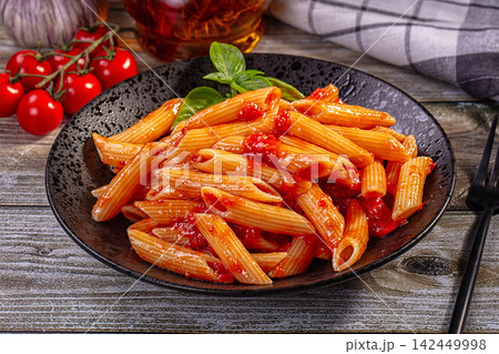 Penne pasta with tomato sauce on rustic plate with basil and cherry tomatoes Penne pasta with tomato sauce on rustic plate with basil and cherry tomatoes 142449998