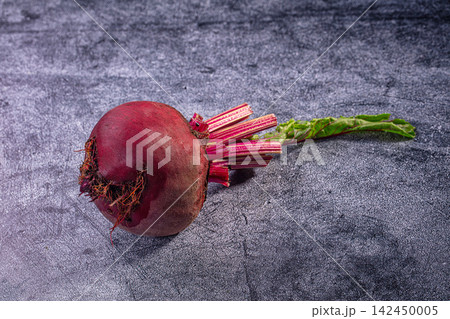 Fresh beetroot with green leaves on textured dark surface Fresh beetroot with green leaves on textured dark surface 142450005