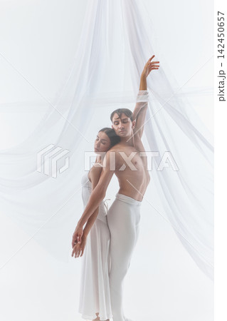 Close dance couple stretches upward in synchronized silhouette Close dance couple stretches upward in synchronized silhouette 142450657