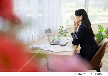 窓辺のデスクで外を眺める若い日本人のビジネスウーマン 窓辺のデスクで外を眺める若い日本人のビジネスウーマン 142450800