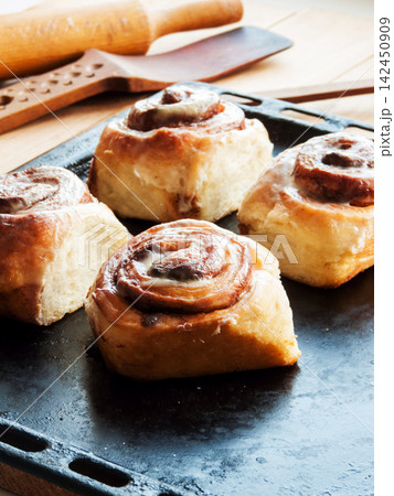 Freshly baked homemade cinnamon rolls with sweet cream cheese lying on oven pan, homemade pasty Freshly baked homemade cinnamon rolls with sweet cream cheese lying on oven pan, homemade pasty 142450909
