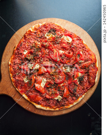 Homemade gourmet pizza with fresh tomatoes, cheese, and herbs on wooden peel 142450965