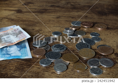 British pounds sterling banknotes and coins on wooden table 142451942